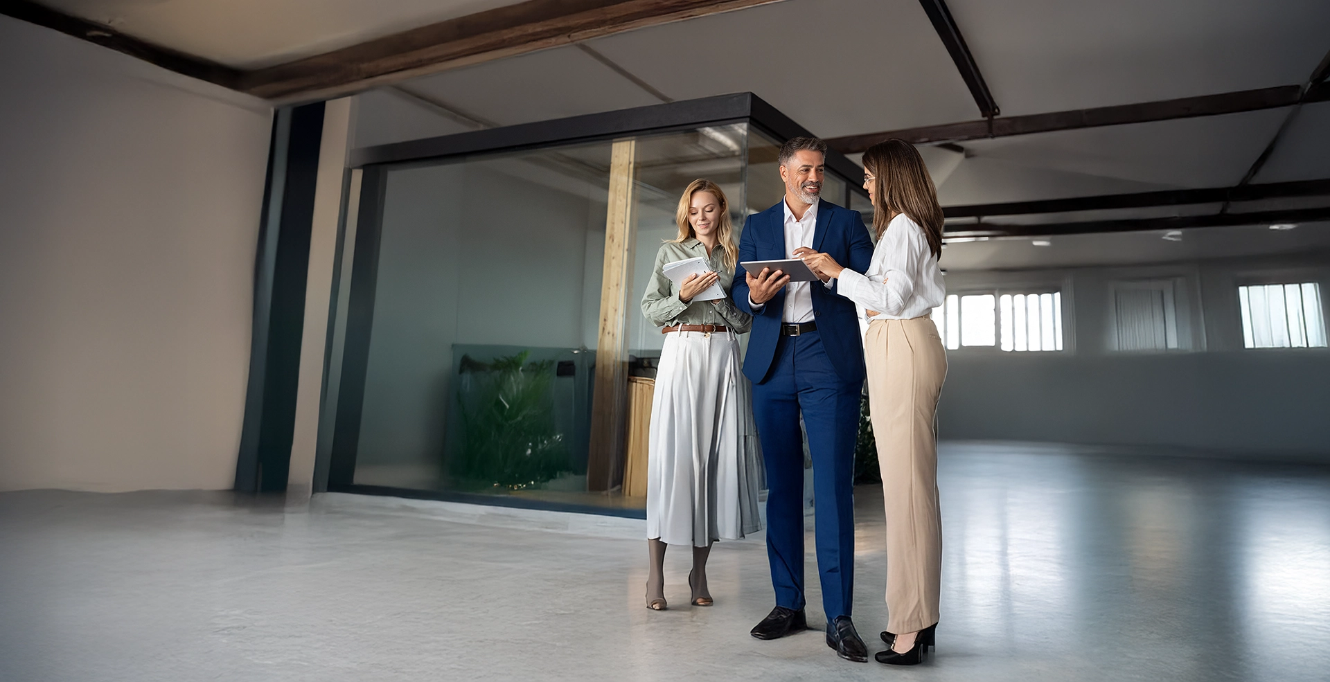 Gruppo di partner diversi, uomo d'affari latino maturo e donna d'affari europea, che discutono dati finanziari e mercato su un tablet in ufficio. Team di colleghi professionisti che lavorano insieme.